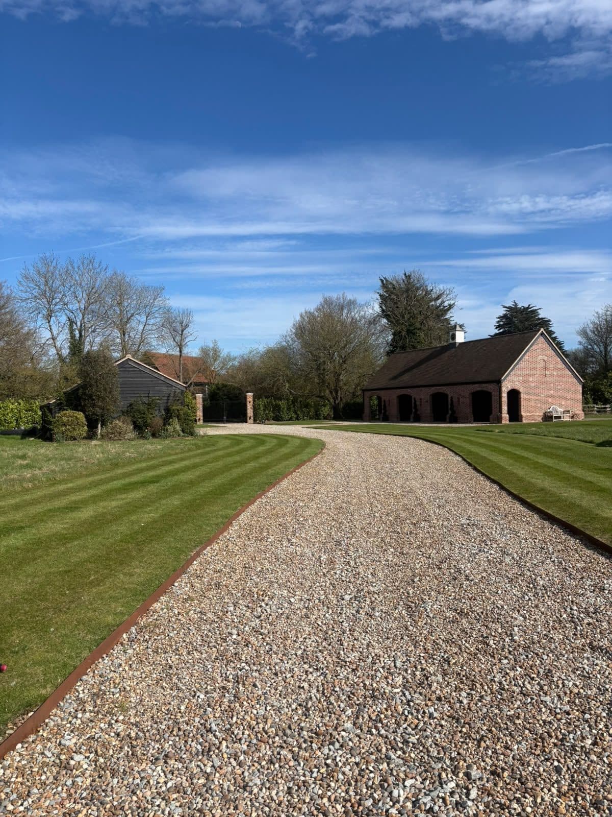 Freshly striped lawns either side of a gravel driveway