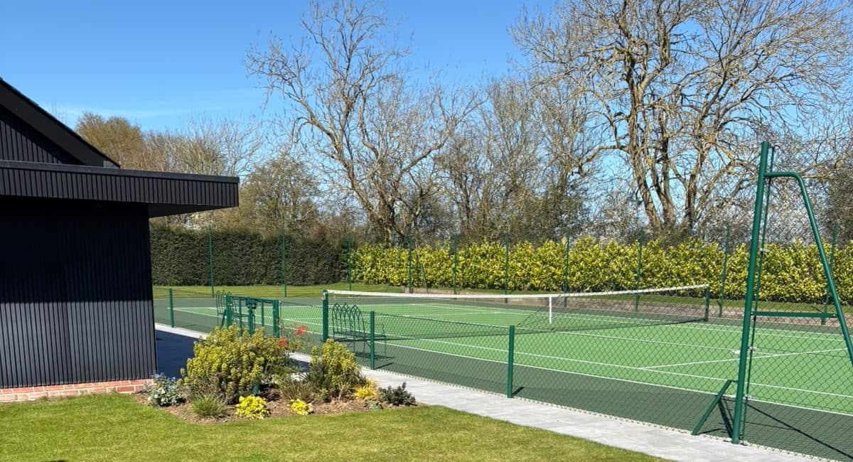 Neatly kept lawn and planted bed beside a tennis court