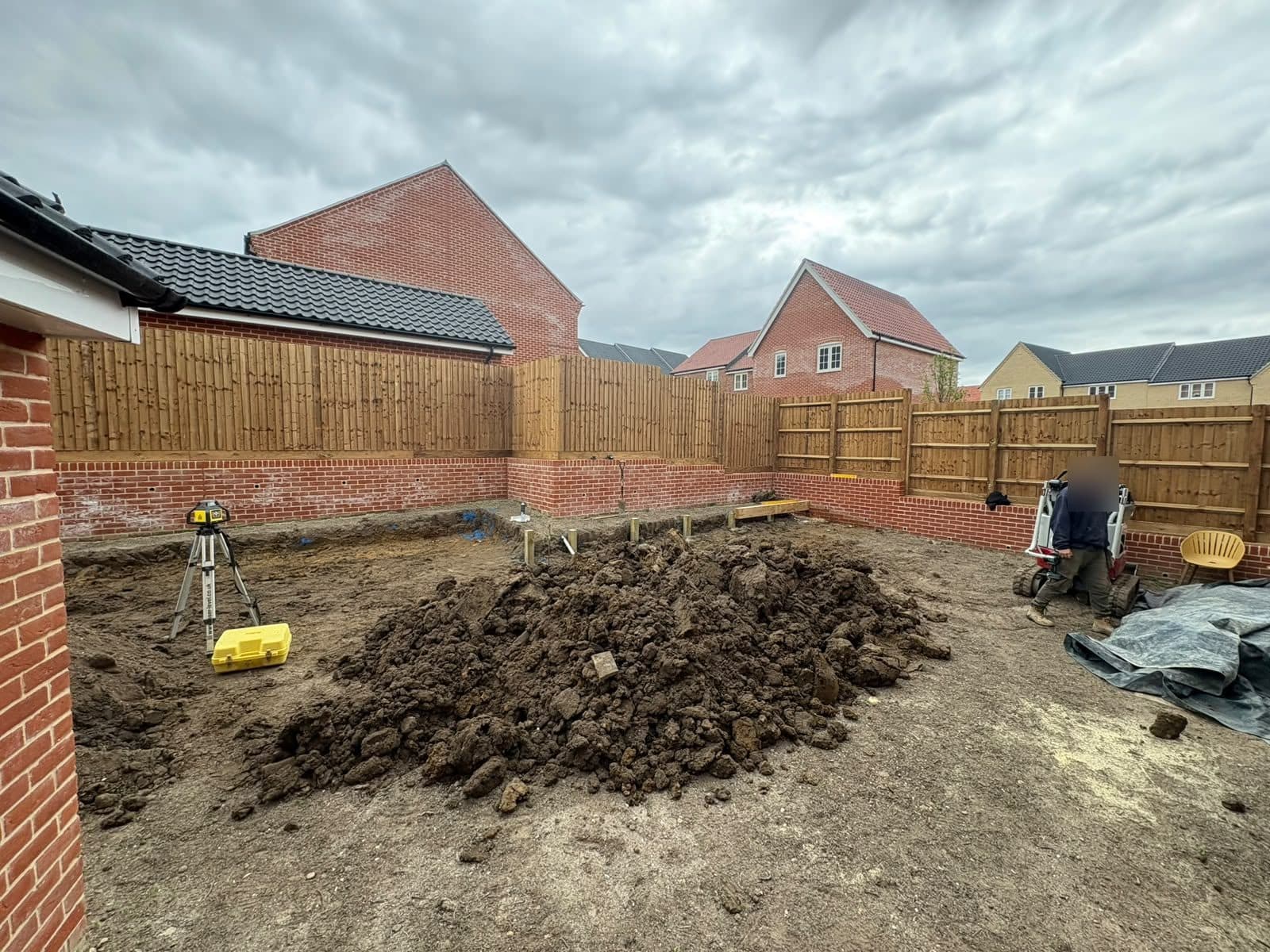 Stepped brick retaining walls with fencing above, during groundworks