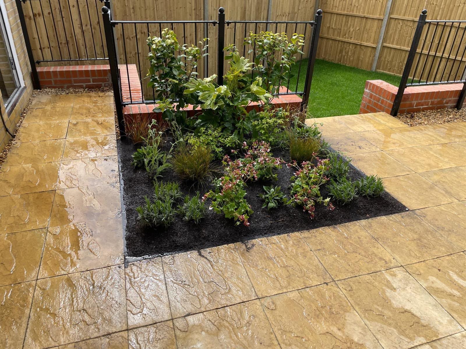 Brick planter walls with railings around a newly planted bed